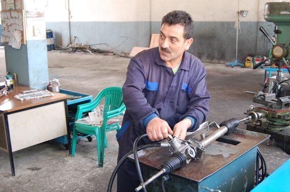 Atölyede hidrolik direksiyon parçası üzerinde çalışan usta